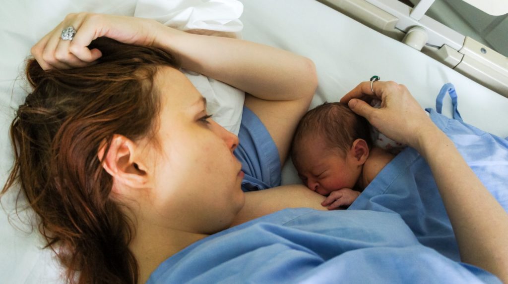 Mother breastfeeding her newborn in hospital bed