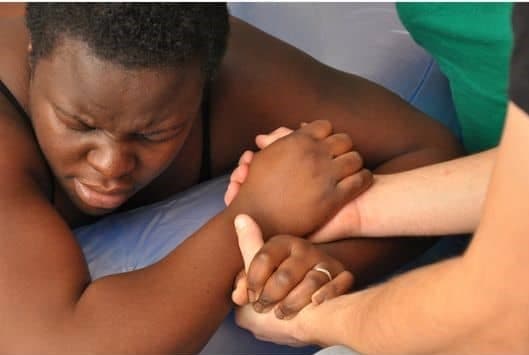 Black woman in labor holding hands with white doctor