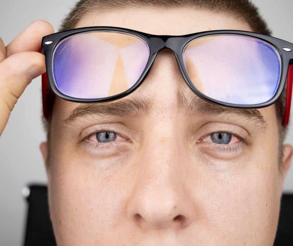 Man with Tired Eyes lifting up blue light glasses
