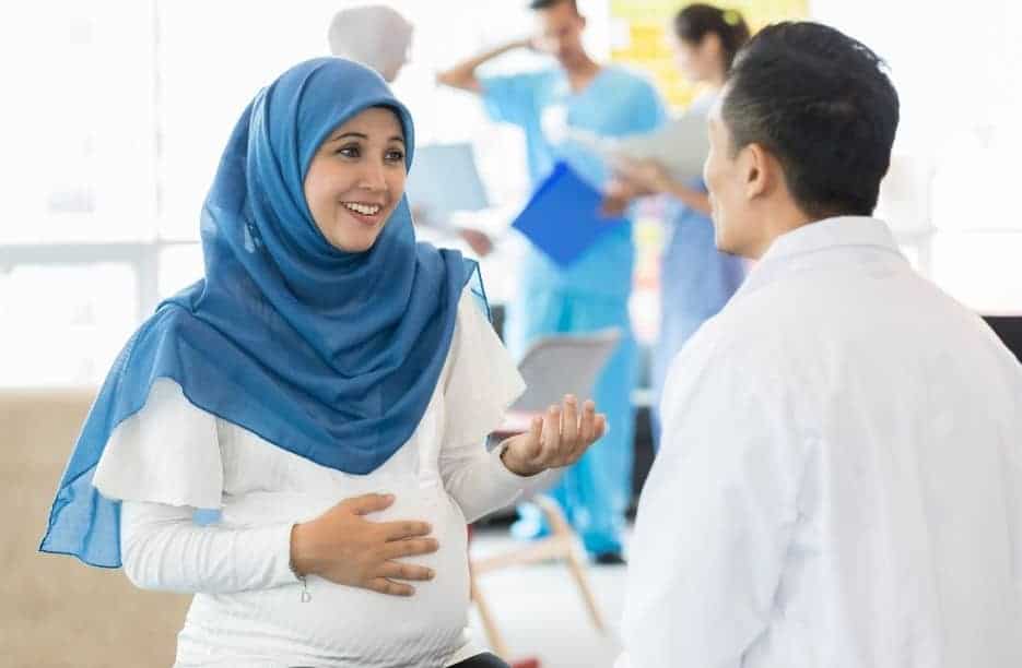 Woman in blue headscarf talking with Male White Doctor