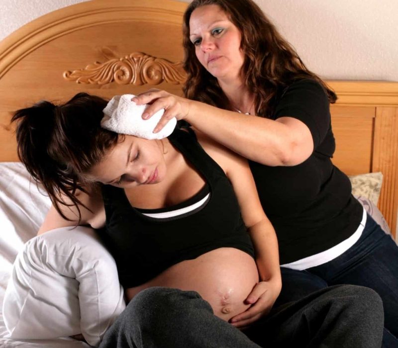 woman laboring at home on her bed with doula