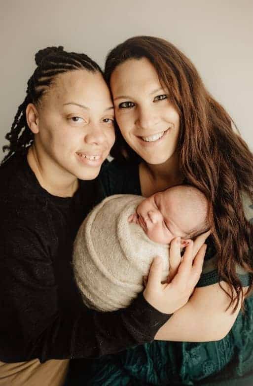 Two mothers, one black holding swaddled baby