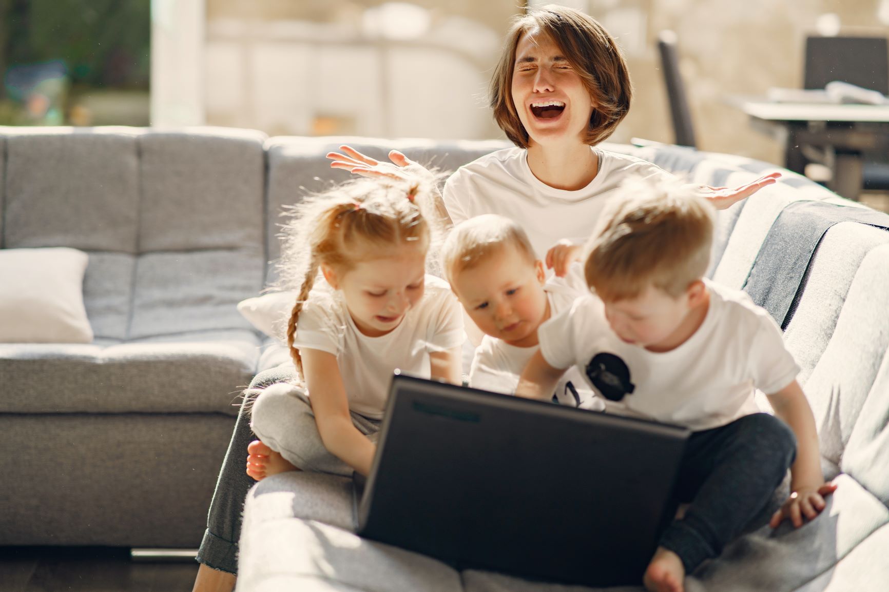 stressed out mm with 3 young children sitting in front of a laptop