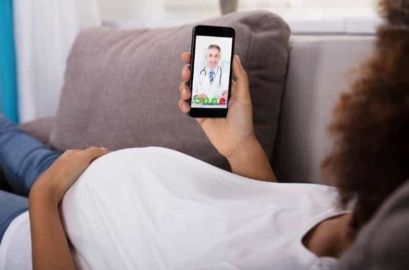 pregnant woman on couch in telemedicine appointment with doctor
