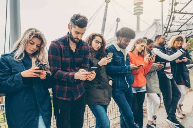 line of five young people all staring at their smartphones